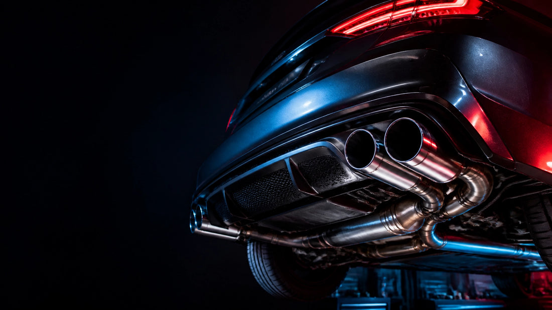 Performance car with polished exhaust tips in a dark automotive workshop