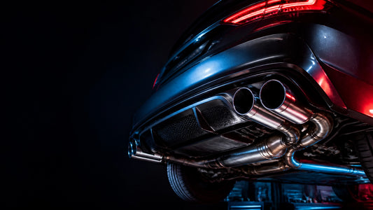 Performance car with polished exhaust tips in a dark automotive workshop