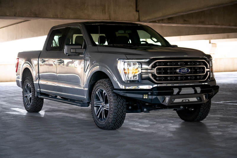 Front view of a 2021 Ford F-150 with a black DV8 MTO Series front bumper installed, highlighting the low-profile design and LED pod mounts.